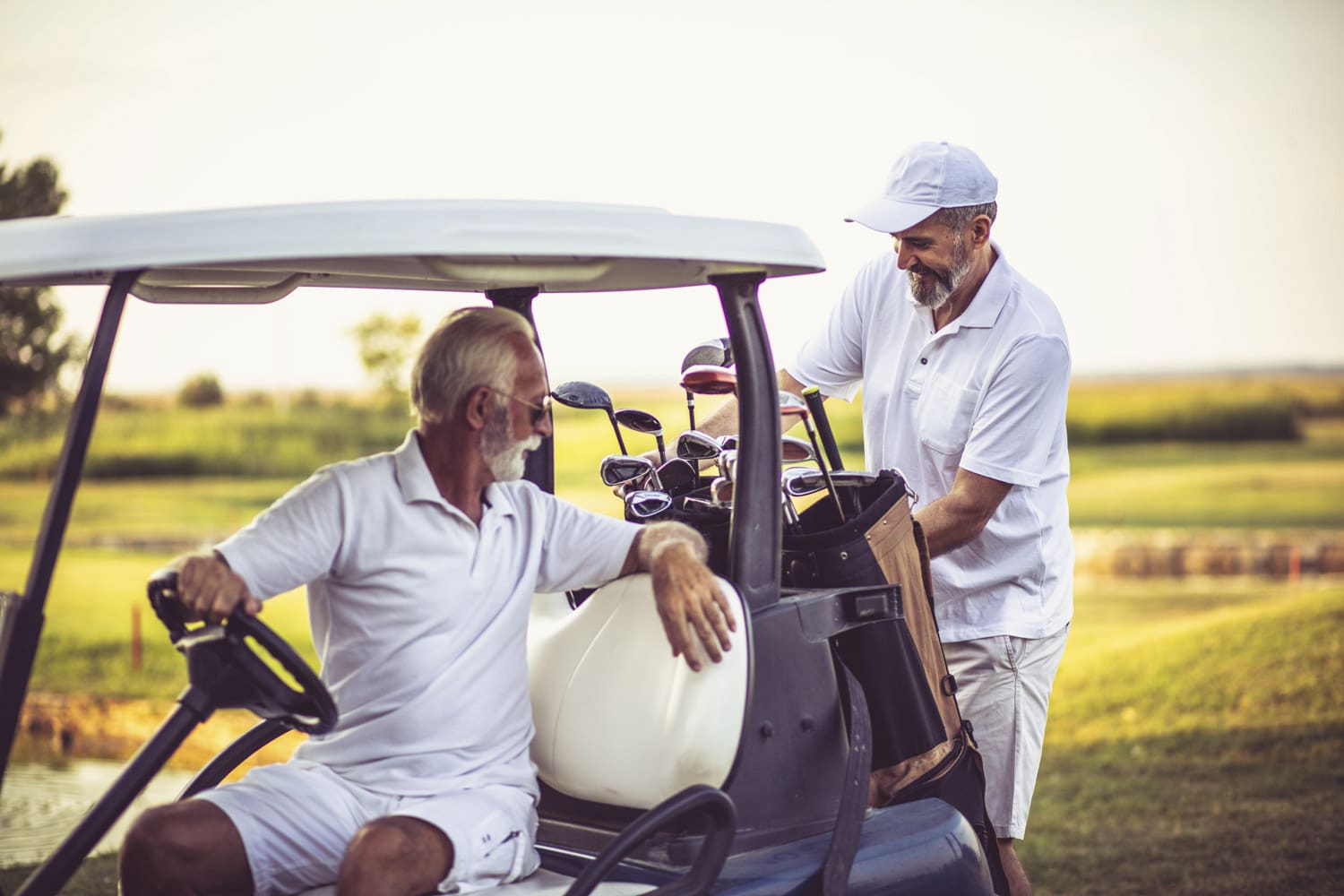 Two senior men golfers on court. Man sitting in golf cart. Phoenix retirement communities