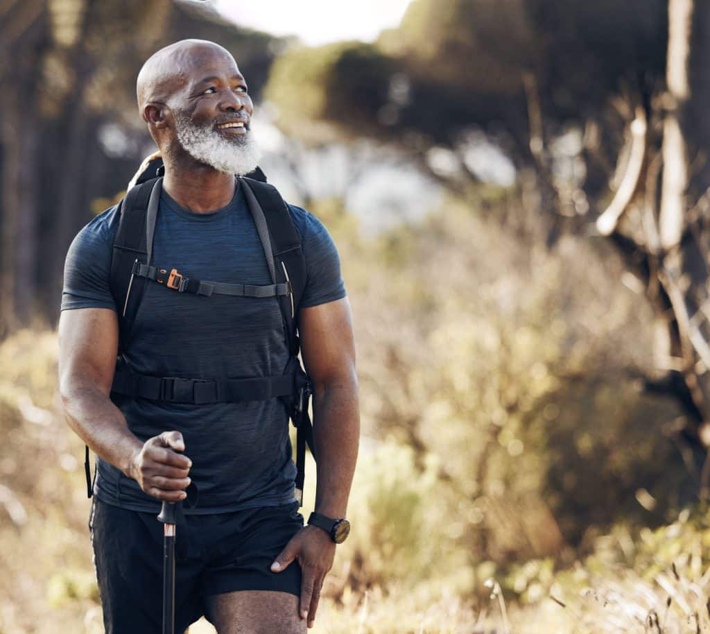 Hiking, black man and travel adventure in nature forest for trekking, fitness and cardio exercise. Senior person with backpack thinking and walking outdoor in woods for travel, health and wellness